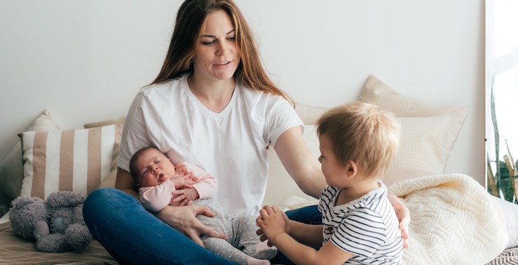 Mother holding a baby and sitting with a young child