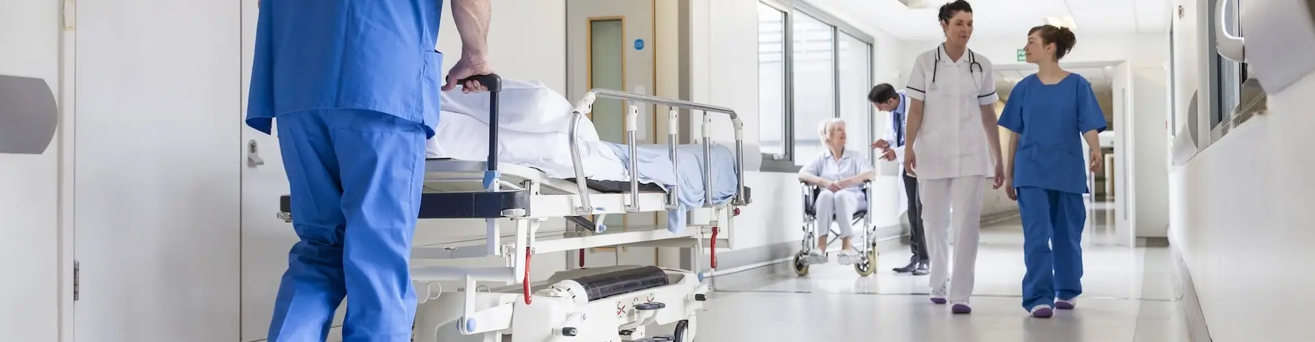 Nurse wheeling trolley down a hospital corridor