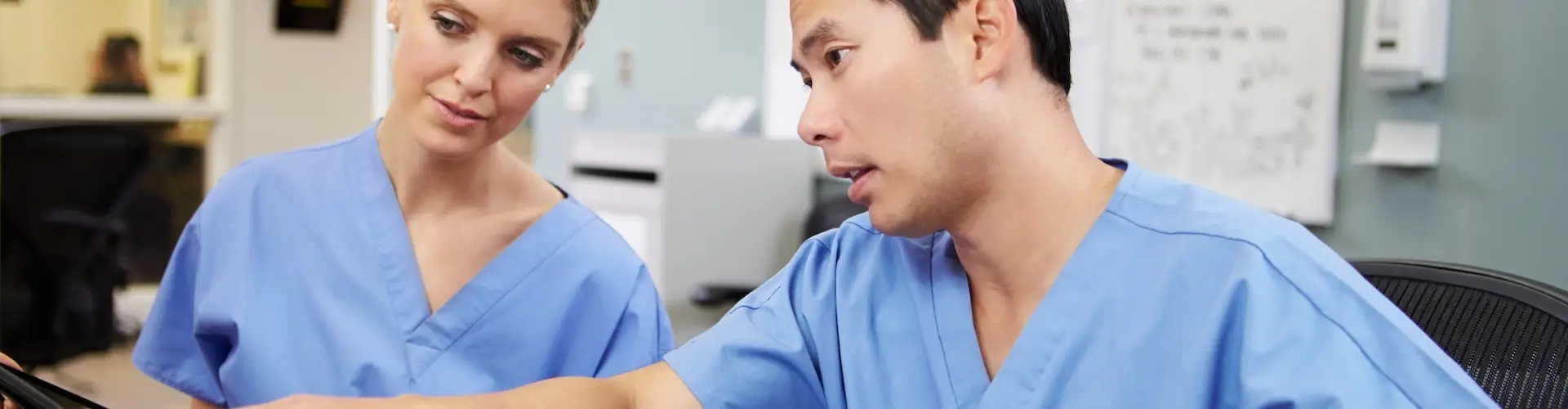 Two nurses analysing data on a computer screen