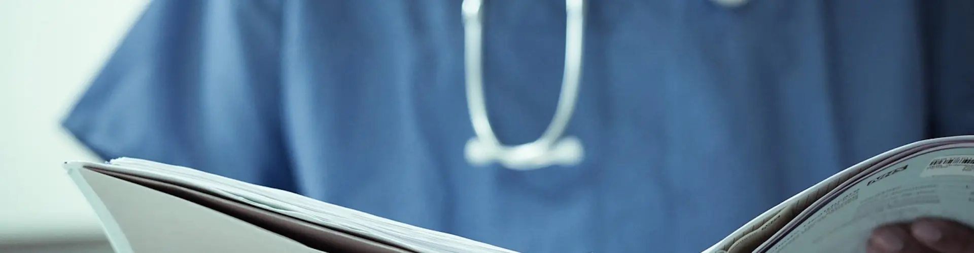 Cropped image of a nurse with stethoscope reviewing a patient file