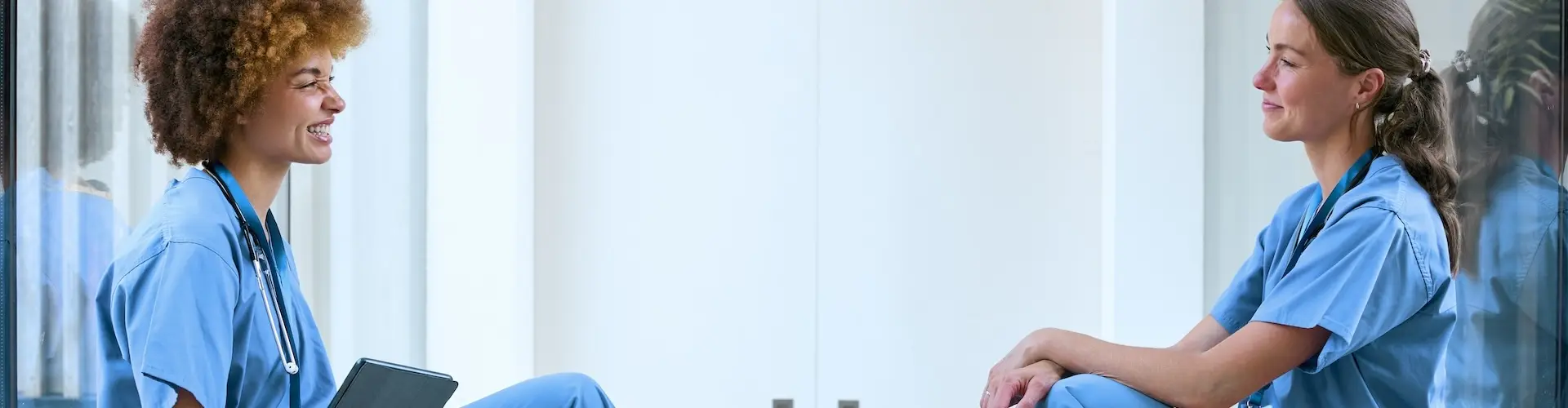 Two nurses sitting chatting in a hospital corridor