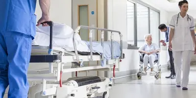 Nurse wheeling trolley down a hospital corridor