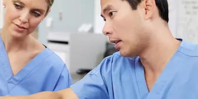 Two nurses analysing data on a computer screen