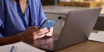 Nurse working with a phone and laptop